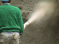 A close-up image of a man spraying the side of a building.